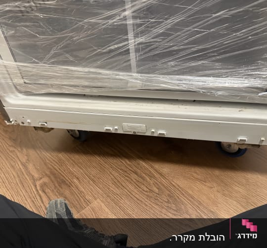 מכשיר עטוף בניילון על גלגלים על רצפת עץ